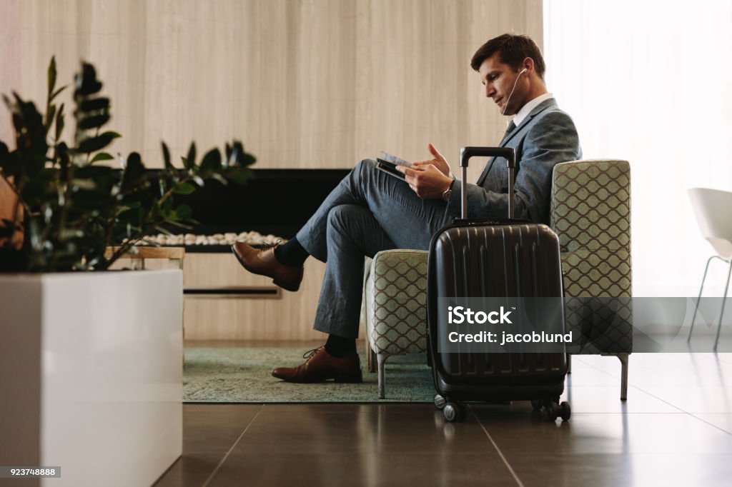 Empresario leyendo revista sala de espera del aeropuerto - Foto de stock de Sala de embarque del aeropuerto libre de derechos