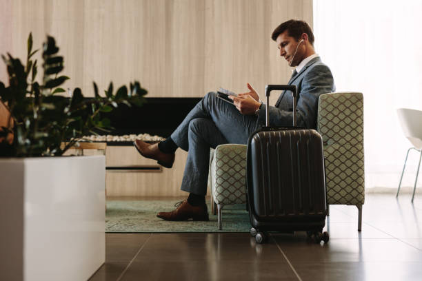 businessman reading magazine in airport waiting room - people traveling business travel waiting airport imagens e fotografias de stock