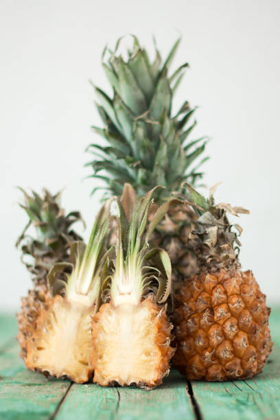 Ripe pineapple and baby pineapple on a wooden background, tropical fruits