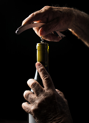 Senior man opening a wine bottle