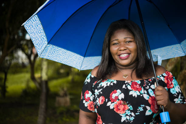 mujer negra con un paraguas azul - chubby cheeks fotografías e imágenes de stock