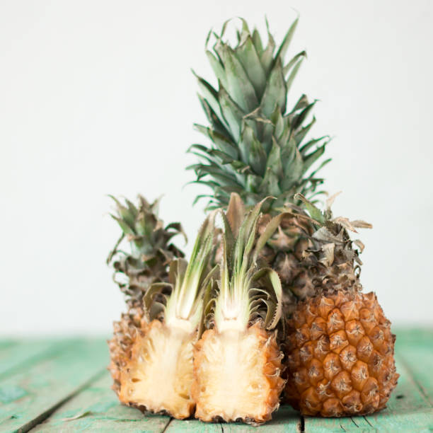 Ripe pineapple and baby pineapple on a wooden background, tropical fruits