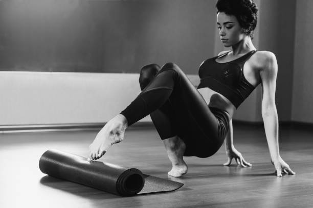 istock woman rolling out yoga mat 923759772