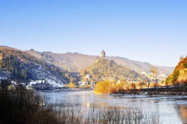 Landscape with houses along the partly frozen Mosel River in  Cochem , a town in the Rhineland - Palatinate in Germany. In the distance the Reichsburg Castle on top of the hill.