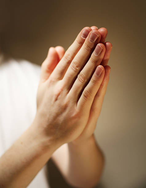 istock Two hands folder in prayer in front of a brown background 92376515