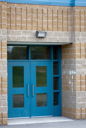 A set of blue school double doors surrounded by grey and brown brick.