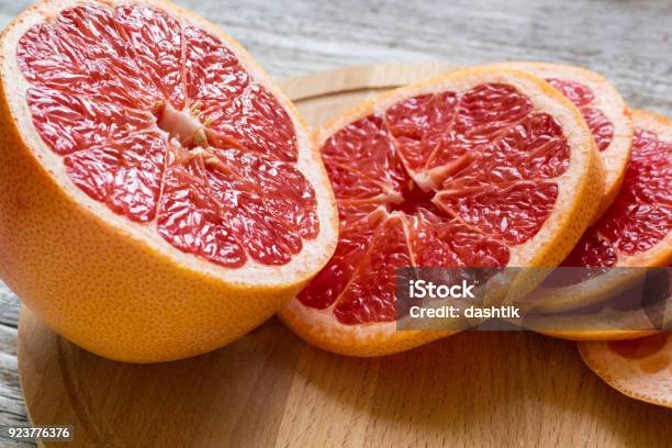 Sliced Pieces Of Grapefruit With A Knife On White Wooden Background Stock Photo - Download Image Now