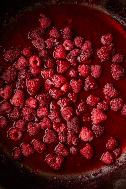 Making-of raspberry jam Close-up view of raspberry jam in a pan raspberry jam stock pictures, royalty-free photos & images