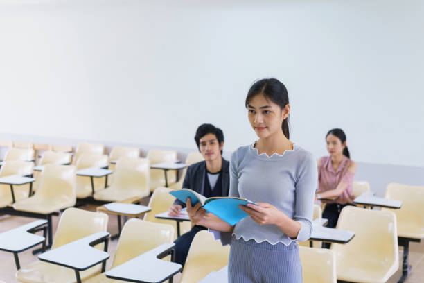 istock Young woman standing present friend student in a classroom showing ready answer. concept of education. 923784564
