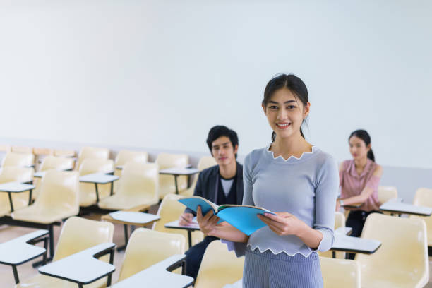istock Young woman standing present friend student in a classroom showing ready answer. concept of education. 923784586