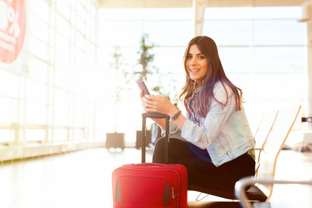 istock Woman smiling and texting using phone, waiting the plane 923795564
