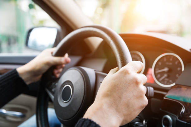 istock Close up of man hands driving a car during sunlight 923796714