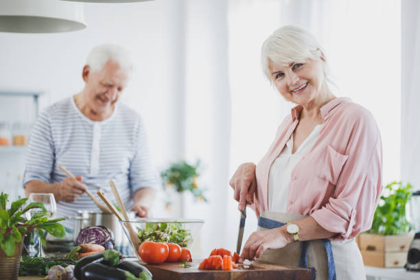istock Smiling senior woman cutting tomatoes 923798936