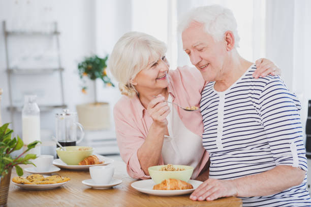 istock Smiling senior woman feeding husband 923798974