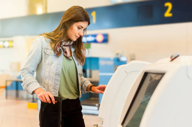 girl in the airport using self service check in machine - airport airport check in counter arrival departure board checkout counter imagens e fotografias de stock