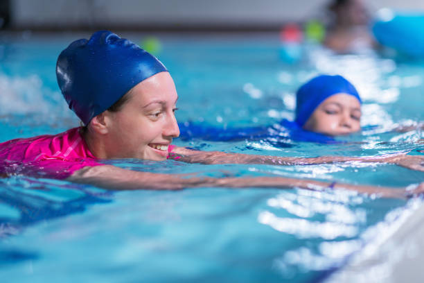 istock Swimming lesson. Cute little boy learning to swim with swimming instructor 923814552