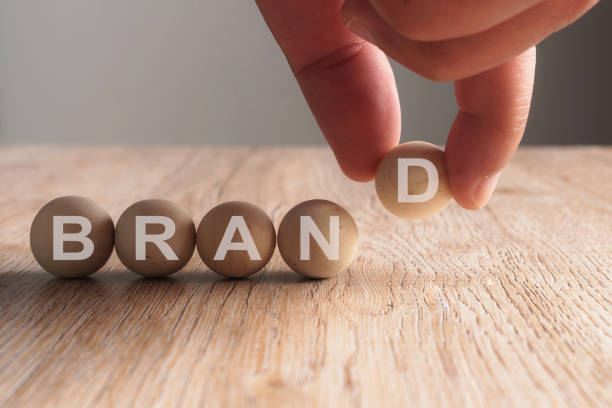 Hand putting on brand word written in wooden ball Hand putting on brand word written in wooden ball military private stock pictures, royalty-free photos & images
