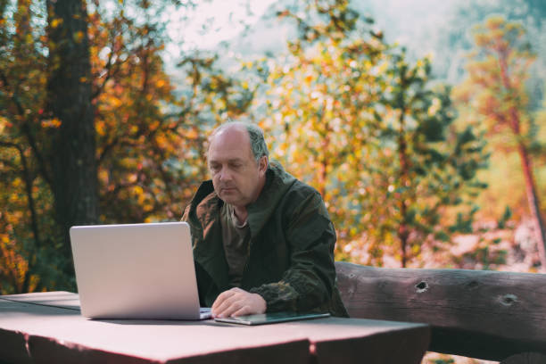 istock Aged hunter in autumn forest with laptop 923827768