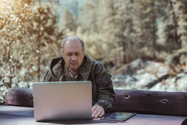 istock Mature male hunter with tablet pc and laptop 923828772