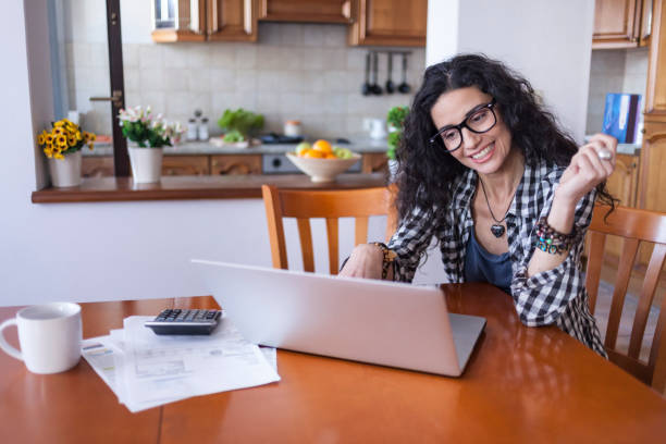 istock Cheerful woman using credit card at home 923831918