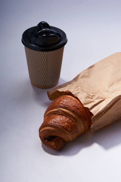 istock Coffee to go and croissant in rustic paper bag on white 923835148