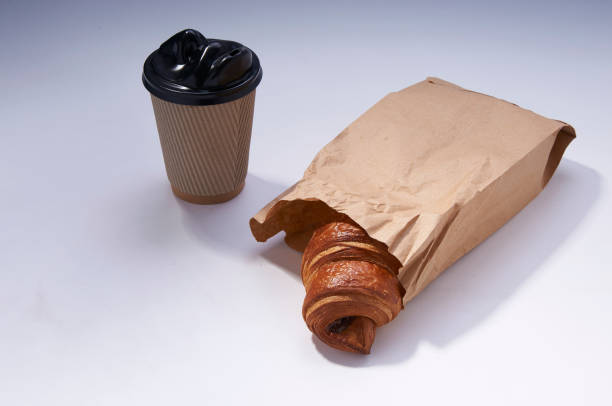 istock Coffee to go and croissant in rustic paper bag on white 923835156