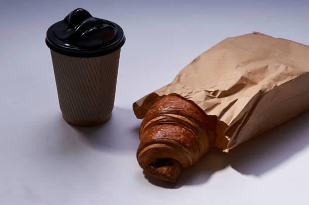 istock Coffee to go and croissant in rustic paper bag on white 923835214