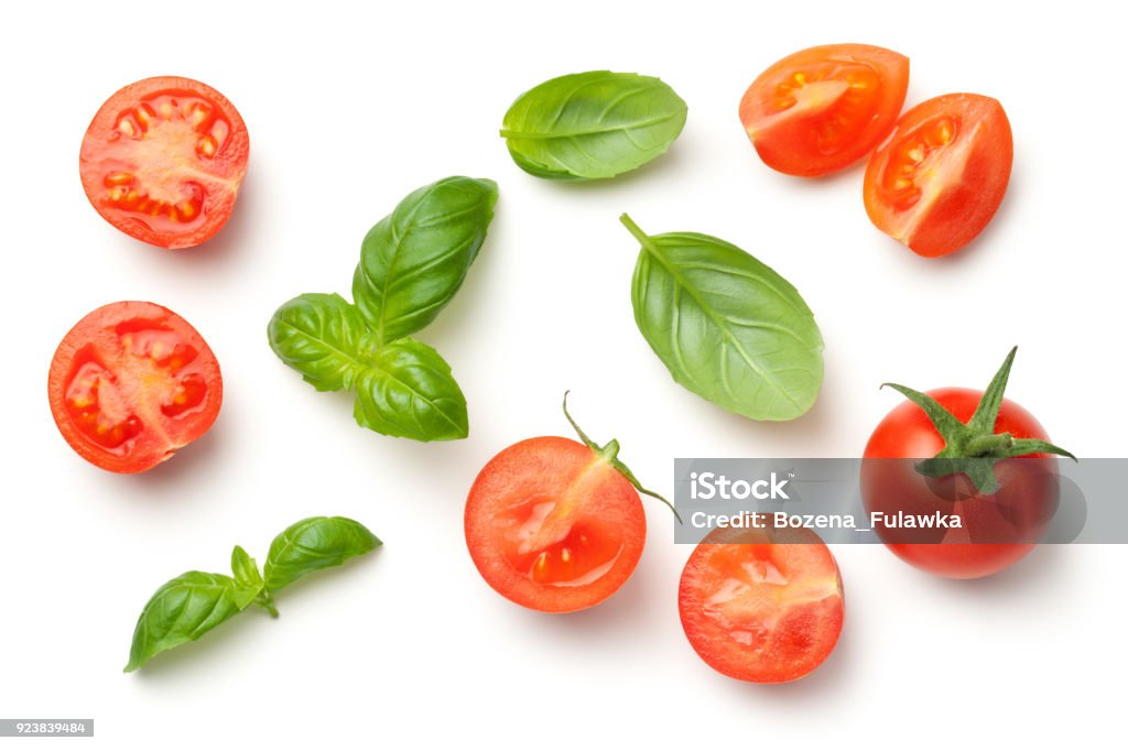 Tomatoes and Basil Leaves Isolated on White Background Tomatoes and basil leaves isolated on white background. Top view Basil Stock Photo