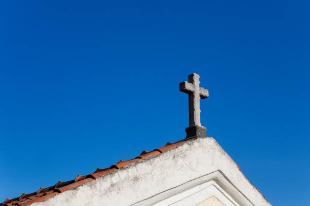 croix sur le toit de l’église avec des tuiles orange contre le ciel - bible stand photos et images de collection