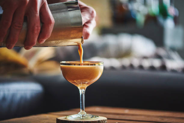 hombre manos vertiendo espresso martini cóctel en vaso - martini fotografías e imágenes de stock