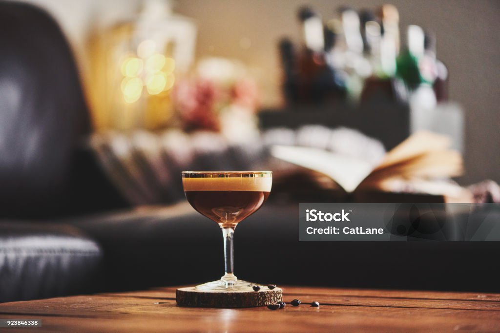 Espresso martini cocktail in indoor setting with coffee beans and book on coffee table Martini Stock Photo