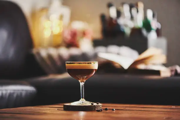 Espresso martini cocktail in indoor setting with coffee beans and book on coffee table