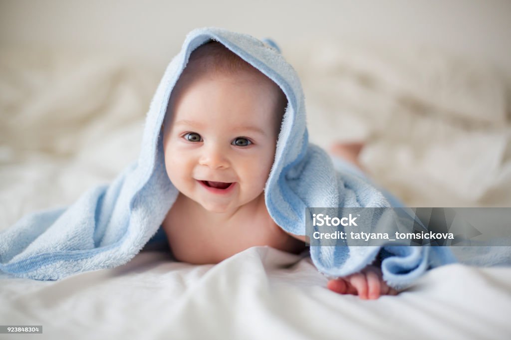 Lindo bebé niño, relajante en la cama después del baño, sonriendo alegremente - Foto de stock de Bebé libre de derechos