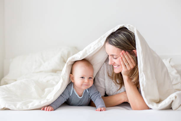 mutter und ihrem kleinen baby-jungen, spielen zusammen in bedrroom - baby blanket fotos stock-fotos und bilder