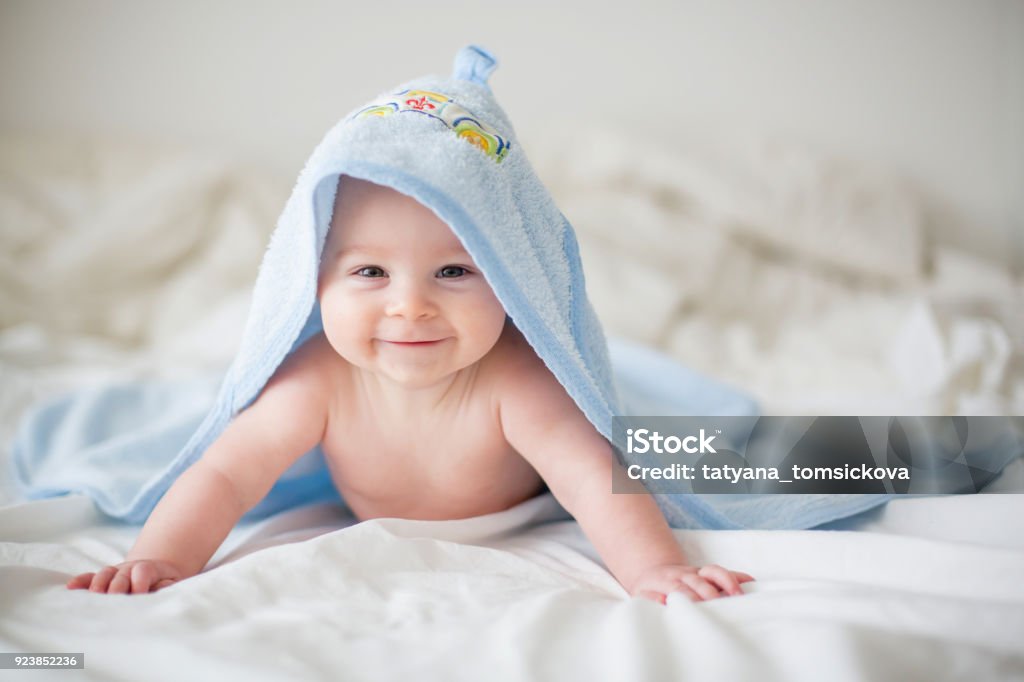 Piccolo bambino carino, rilassante a letto dopo il bagno, sorride felicemente - Foto stock royalty-free di Bebé