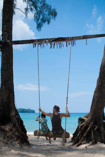 istock Father and daughter playing on the beach swing 923859084