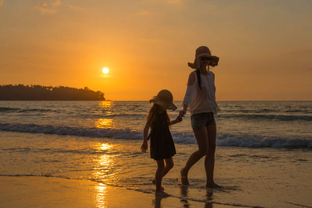 istock Mother and daughter walking in the sunset coast 923862544