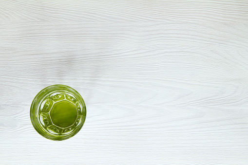 Clean water in a green glass on a white wooden table top view