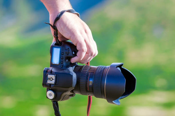 istock Hand of a man holding professional digital camera on blurred gre 923873184