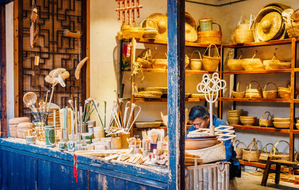At the Zhouzhuang Water Town, Suzhou, China Suzhou, China - Nov 5, 2016: Man sitting behind his store quietly making handicrafts for sale at the historic Zhouzhuang Water Town. Zhouzhuang more than 900 years old and is an UNESCO World Heritage site. water town zhouzhuang china stock pictures, royalty-free photos & images
