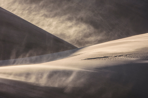 Sand blowing off the top of a sand dune