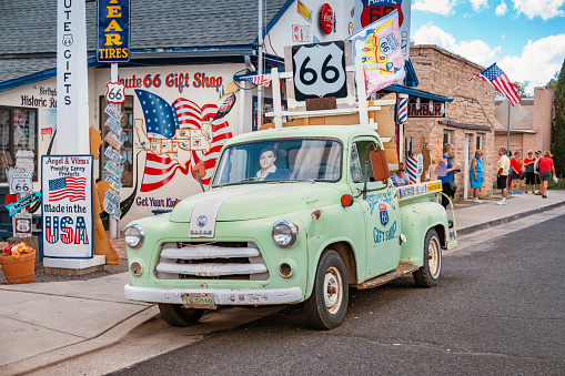 Classic pickup-truck parked on Historic Route 66 with tourists looking around in the background in Seligman Arizona