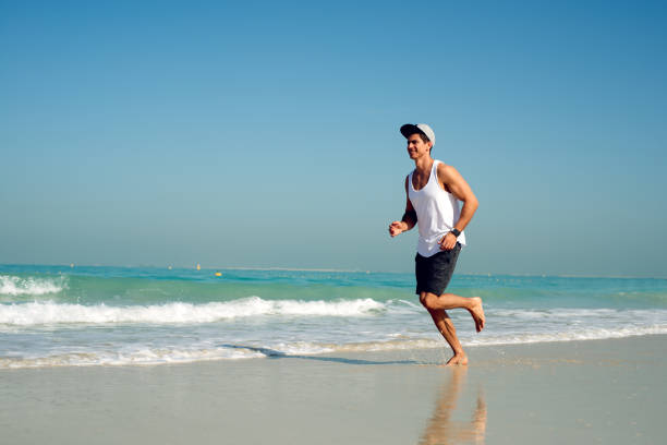 istock Young handsome man wearing a cap while running on the beach. 923918690