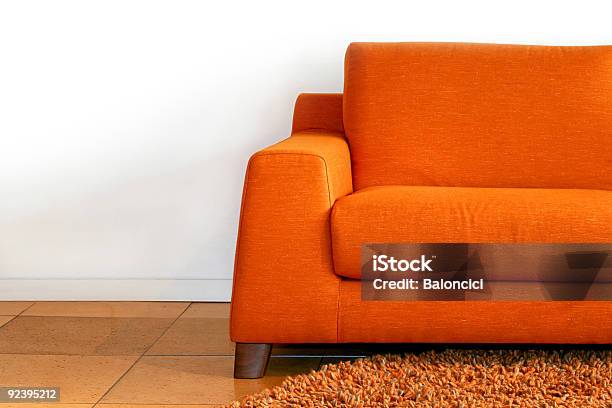 Orange Sofa With A Rust Colored Rug And White Walls Stock Photo - Download Image Now