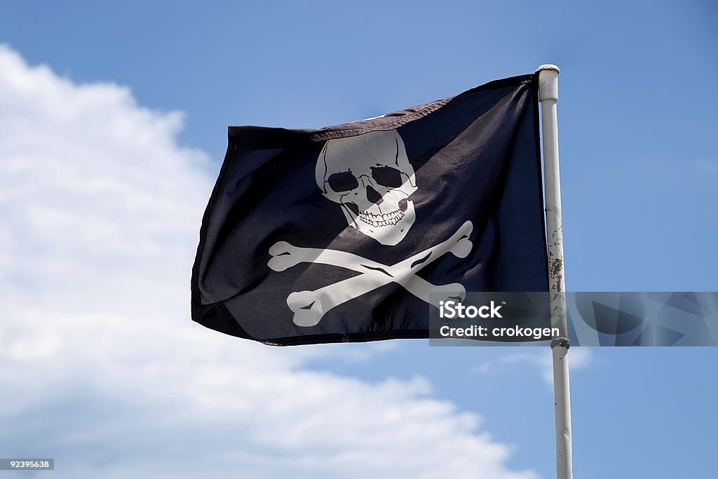 Jolly Roger bandera contra el cielo azul - Foto de stock de Azul libre de derechos