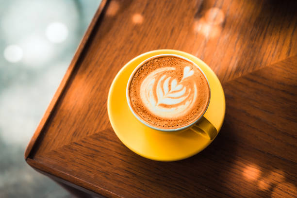 istock Latte art coffee in a yellow cup on a wooden table 923956524