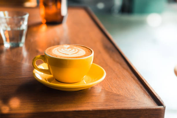 istock Latte art coffee in a yellow cup on a wooden table 923956532