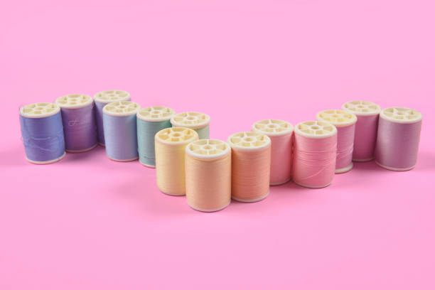 istock Flat lay of colored thread rolls for sewing on pink background, Sewing and needlework concept. 923971188