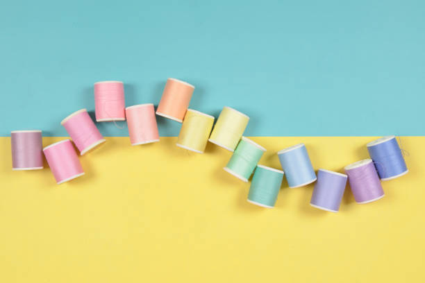 istock Flat lay of colored thread rolls for sewing on two tone background, Sewing and needlework concept. 923971238