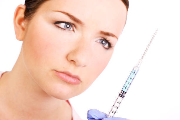 Nurse looking at a syringe stock photo